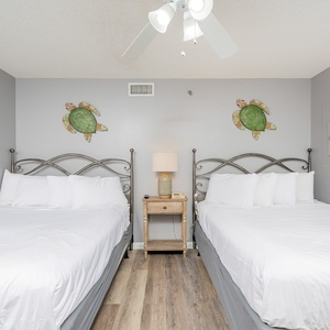 Cheerful guest room featuring two double beds, turtle decor, and a nightstand with a lamp