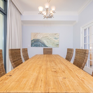 Dining area featuring a rustic wooden table, woven chairs, and coastal artwork, perfect for family gatherings