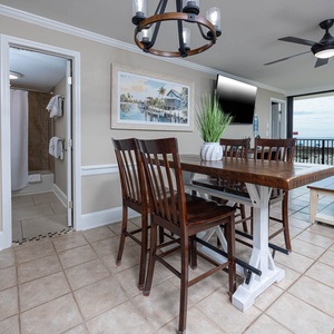 This dining area features a wooden table, comfortable seating, and a view of the beach through large windows