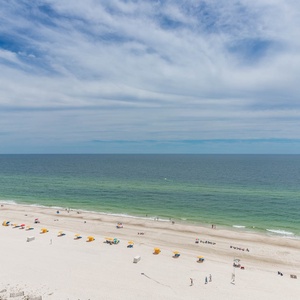 Vibrant umbrellas dot the white sand beach, inviting guests to enjoy the serene coastal view and gentle waves
