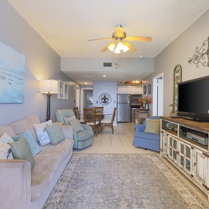 The living area features a comfortable sofa, a large TV, and a dining space, perfect for relaxation and gatherings