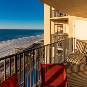 The balcony features a lounger and patio set, offering a serene view of the beach and tranquil waters