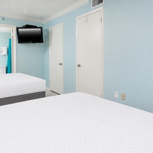 Relax in the inviting guest room with two double beds, a TV, and a calming blue color scheme