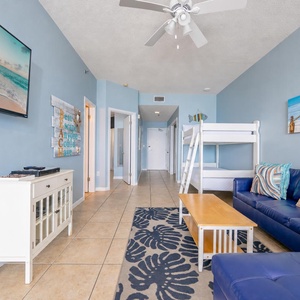 Bright living area featuring a cozy sofa, a TV, twin bunk bed, and a coffee table with beachfront views