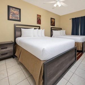 Rest comfortably in this inviting guest bedroom with two double beds, stylish decor, and a warm vibe for a restful sleep