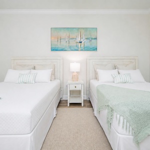 Tranquil guest bedroom featuring two comfortable queens, soft linens, and a serene coastal-themed painting