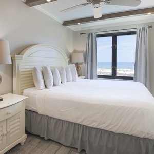This bedroom features a comfortable king bed, stylish decor, and a stunning beachfront view through large windows