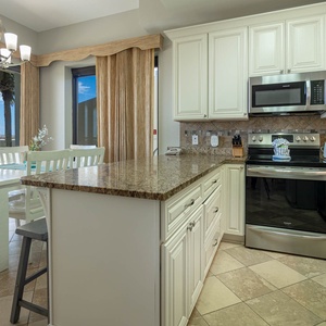 Dining area features a white table with matching chairs, complemented by a view of palm trees and the outdoors