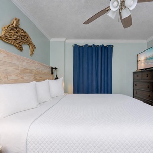 Cozy master bedroom featuring a king bed, elegant wooden furnishings, and a wall-mounted TV for relaxation and entertainment