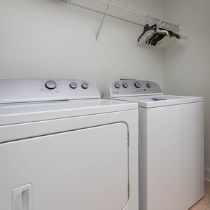 Laundry area featuring a Whirlpool washer and dryer, along with a shelf for convenient storage of hangers and essentials