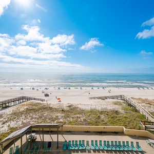 The balcony view showcases the sandy beach and vibrant umbrellas, perfect for relaxation and fun in the sun