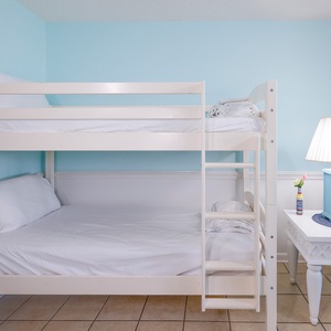 Brightly colored bunk bed with fresh linens, complemented by a stylish nightstand and lamp