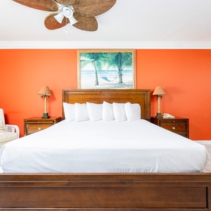 Relax in the master bedroom featuring a king bed, tropical decor, and a cozy reading nook with beachfront balcony access