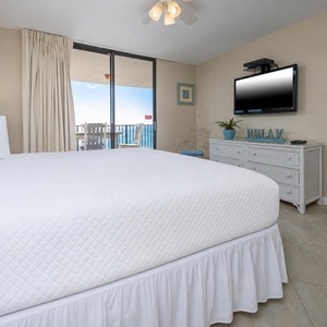 Tranquil master bedroom featuring a king bed, a TV, and access to a balcony with a lovely view