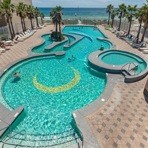 This vibrant pool area features a winding design, inviting loungers, and a stunning beach view for a perfect relaxation spot