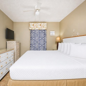 The master bedroom features a large bed, a mounted TV, and charming coastal decor, perfect for a relaxing getaway