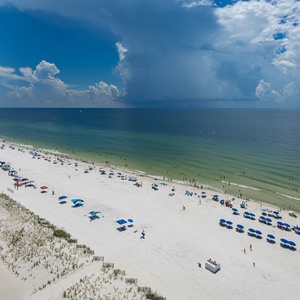 Gaze at the inviting shoreline, where colorful umbrellas dot the beach and guests enjoy the refreshing waters