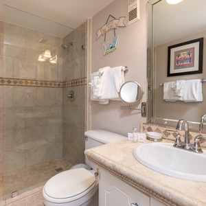 This bathroom features a stylish glass shower, elegant tile accents, and a well-lit vanity for a refreshing experience