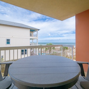 Enjoy a relaxing view of the beach from the cozy balcony with stylish seating and a round table