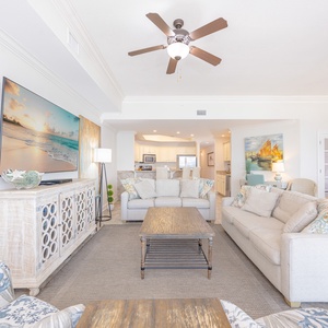 Living space featuring a large TV, cozy seating, and a view into the modern kitchen area