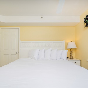 This bright bedroom features a king bed with plush pillows, a cozy lamp, and a stunning beachfront view from the window