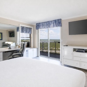 Master bedroom featuring a king bed, a desk with a chair, and a sliding door leading to a balcony with scenic views