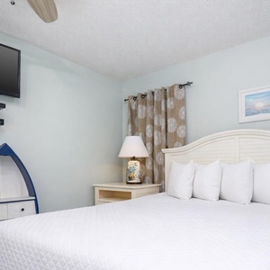 This guest bedroom features a plush bed, a mounted TV, and charming nautical decor, perfect for a relaxing stay