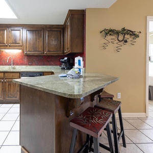 Prepare meals in the inviting kitchen with rich wood cabinetry, a spacious countertop, and stylish breakfast bar