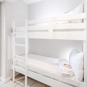 Relax in this charming bunk space in the hallway, perfect for kids, featuring two cozy bunk beds with fresh linens