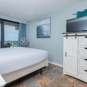 This inviting bedroom features a comfortable bed, a stylish dresser, and stunning beachfront views through large windows