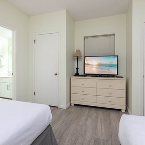 Inviting guest room featuring two double beds, a TV, and easy access to a stylish bathroom