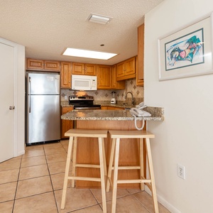 Gather around the breakfast bar with stools, enjoying the warm wood tones and granite countertops in this inviting kitchen