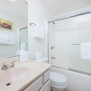 Refresh in this guest bath with spacious glass-enclosed tub-shower combo and fresh towels