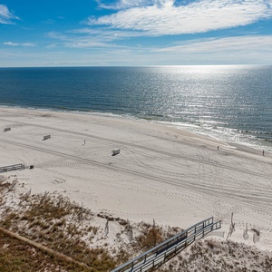 Expansive beachfront view showcasing soft white sand and gentle waves under a clear blue sky, perfect for relaxation