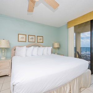 Spacious master bedroom features a king bed with plush pillows and a balcony offering a serene view of the beach