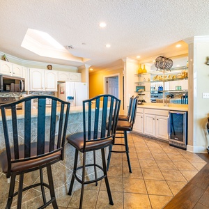 A breakfast bar with tall chairs invites you to sip drinks and chat in the bright kitchen space