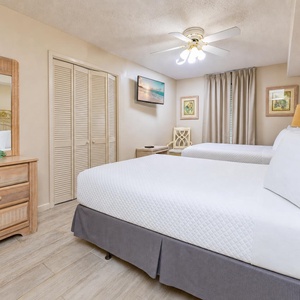 Guest bedroom featuring two full beds with ornate yellow metal headboards, soft linens, and warm lighting