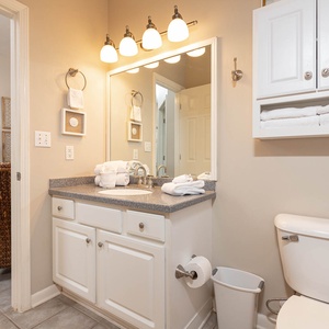 The bathroom features a spacious vanity with a large mirror, neatly arranged towels, and ample storage for essentials