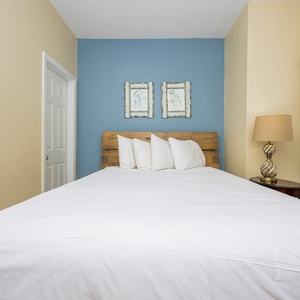 This guest bedroom features a wooden headboard, soft white bedding, and charming artwork, perfect for restful nights