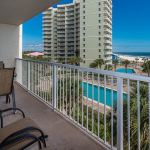 Enjoy a relaxing view from the balcony with comfortable seating overlooking the pool and beach