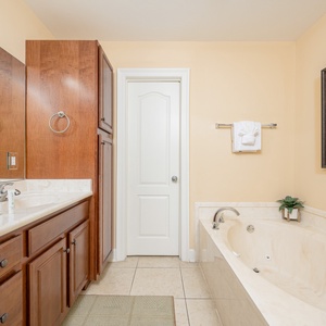 Relax in this elegant master bath featuring a jetted tub, walk-in shower, stylish cabinetry, and soothing neutral tones