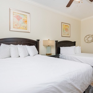 This guest bedroom features two comfortable queen beds, soft linens, and colorful artwork, creating a relaxing atmosphere