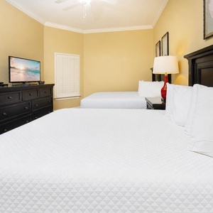 Guest bedroom featuring two comfortable queen beds, a flat-screen TV, and warm yellow walls for a relaxing stay