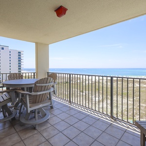 Balcony with a round table and chairs offers a serene view of the beach and gulf, perfect for relaxing moments outdoors