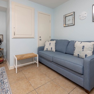 A cozy blue sofa with seahorse-patterned pillows complements the master bedroom with an addiitonal queen sleeper
