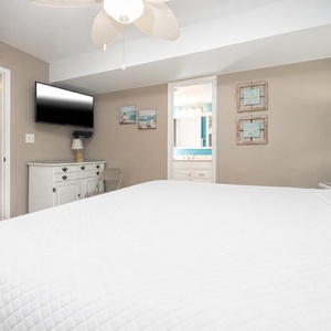 The bedroom featuring a plush king bed, flat-screen TV, and beach-themed decor for a relaxing getaway experience