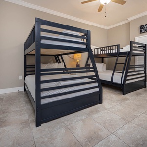Charming bunk room with two twin beds above two cozy double beds below, adorned with fun coastal decor