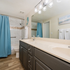 Refresh in the spacious guest bathroom featuring dual sinks, a stylish tub-shower, and elegant tile accents