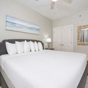 Inviting guest bedroom featuring a large king bed with multiple pillows, stylish decor, and a cozy bedside lamp