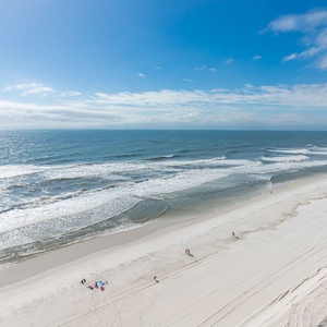 This stunning beachfront view showcases gentle waves lapping against the soft, white sand, perfect for relaxation